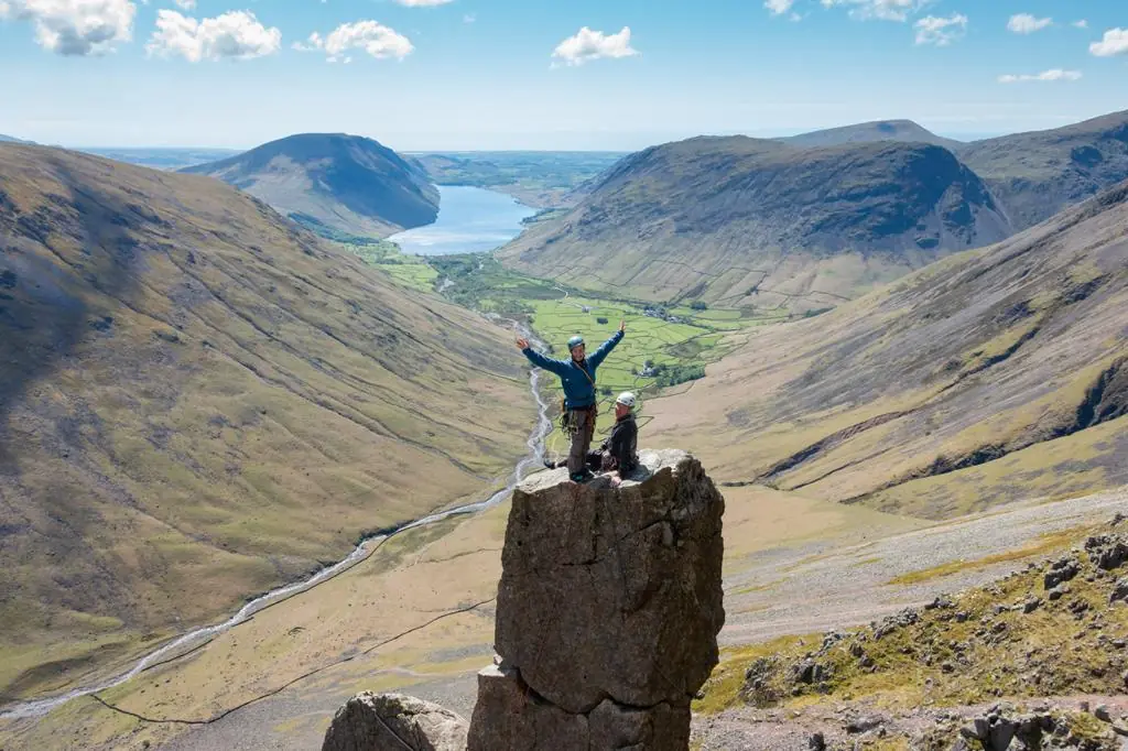 Climber on a rock pinnacle overlooking a mountain valley