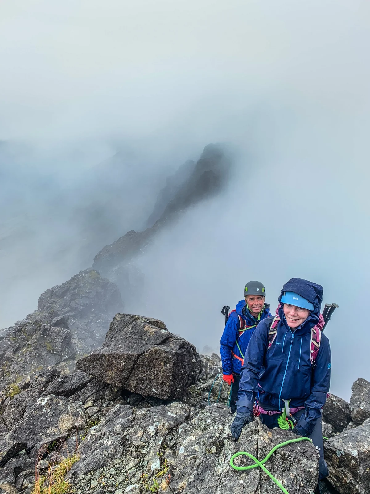 Two helmeted mountaineers on a rocky ridge in mist
