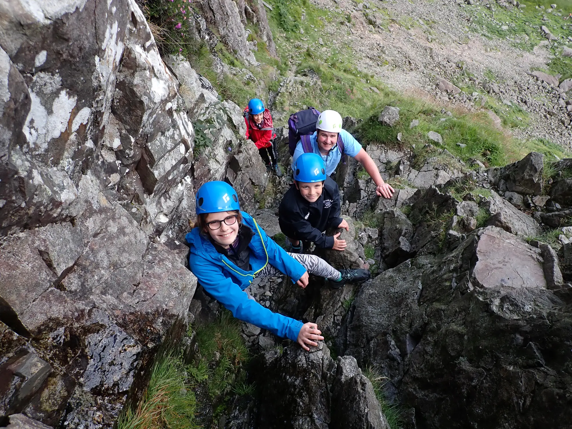 Three people scrambling on a rocky mountainside