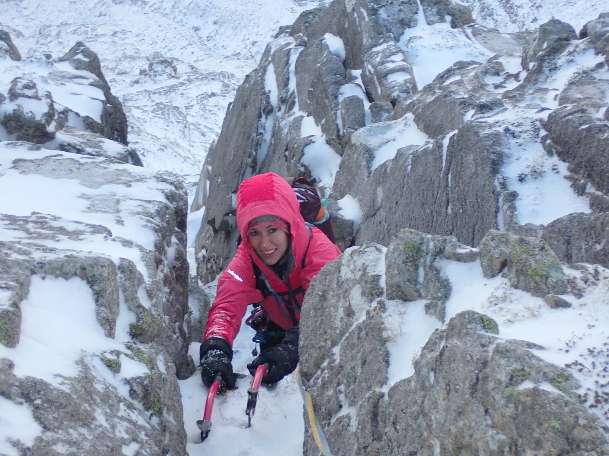 Winter climber using ice tools in a snow-covered rocky gully