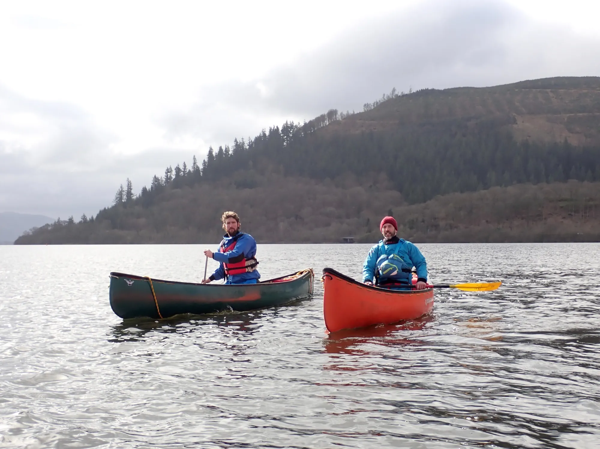 Two paddlers in open canoes on a lake