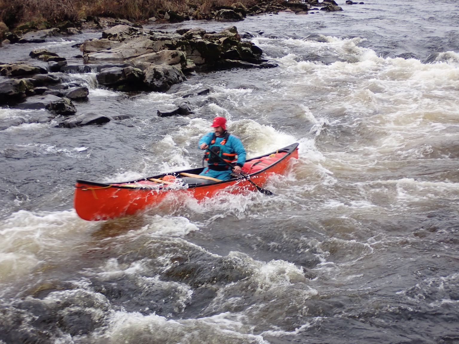 Canoeist paddling whitewater in an open canoe