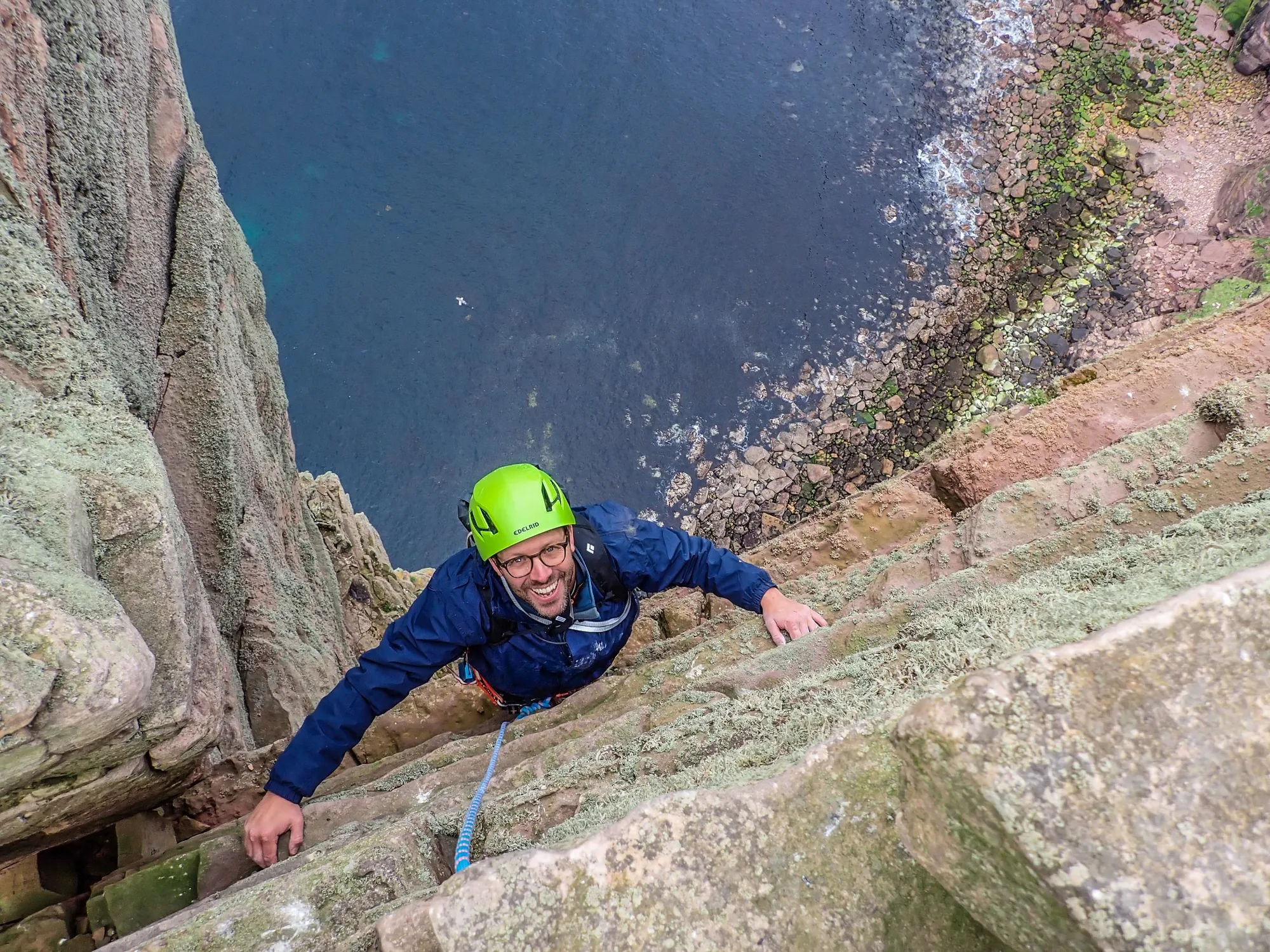 Climber on a sea stack above the rocky shoreline